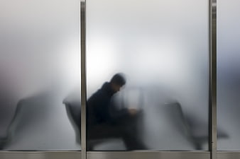 Blurred silhouette of a traveler waiting behind frosted glass