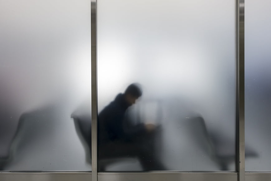 Blurred silhouette of a traveler waiting behind frosted glass