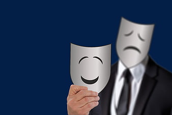Businessman holding smiling mask over sad face