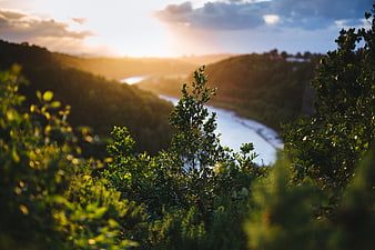 Sunset over a winding river valley with lush green hills