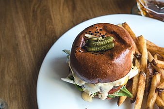 Gourmet Burger with Pickles and Fries on White Plate