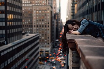 Sad woman sleeping on balcony overlooking city traffic