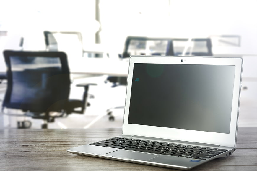 Silver laptop on wooden desk in bright modern office