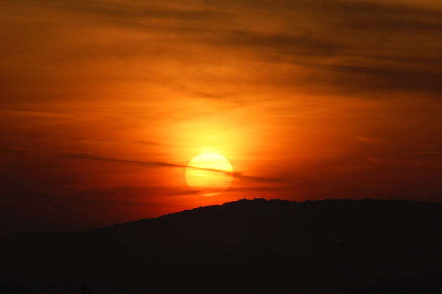 Vibrant orange sunset over dark mountain silhouette