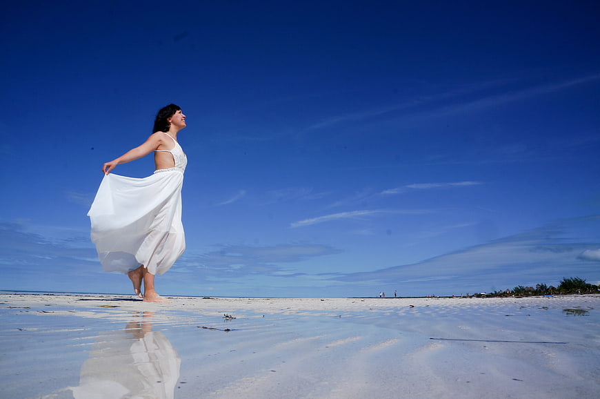 Young Woman In White Dress Walking On Tropical White Sand Beach