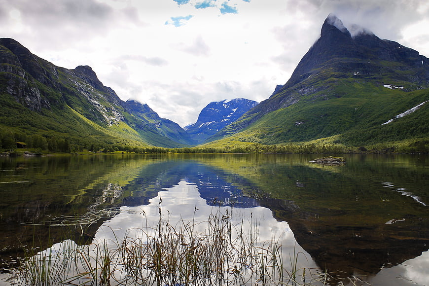 Serene mountain lake with perfect reflection and lush green valley