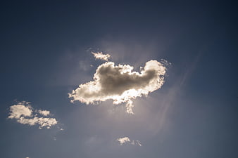 Sun rays bursting through white cloud in blue sky