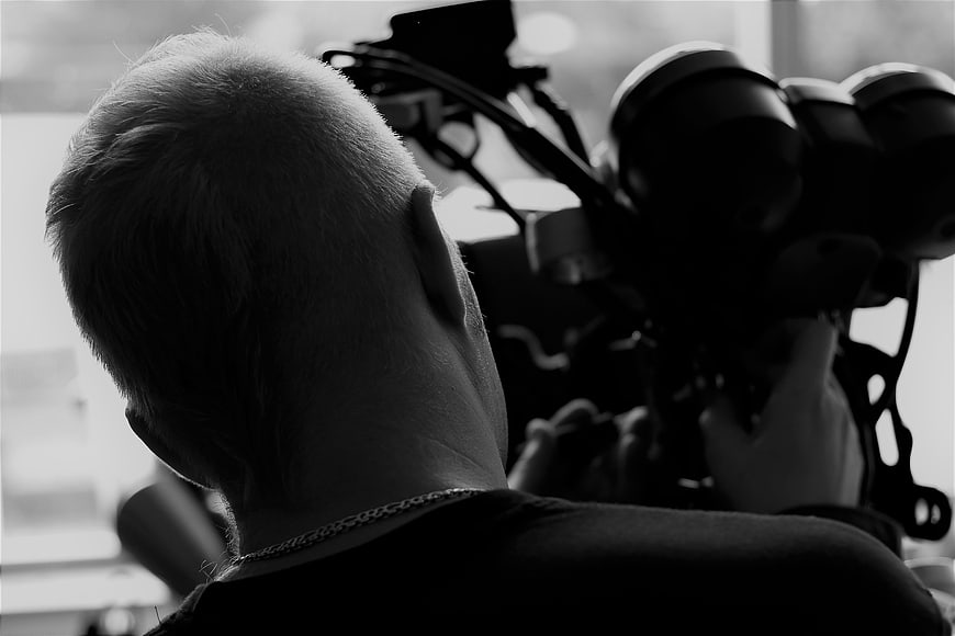 Cinematic black and white shot of a man operating a professional video camera