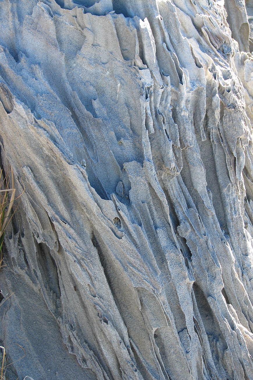 Closeup of blue-gray eroded rock texture with vertical striations