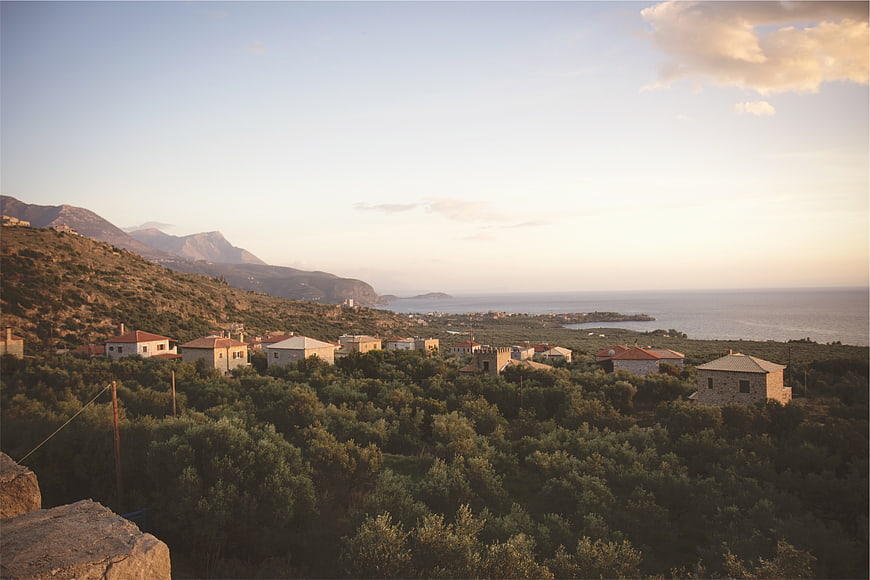 Scenic coastal village with olive groves and mountains at sunset