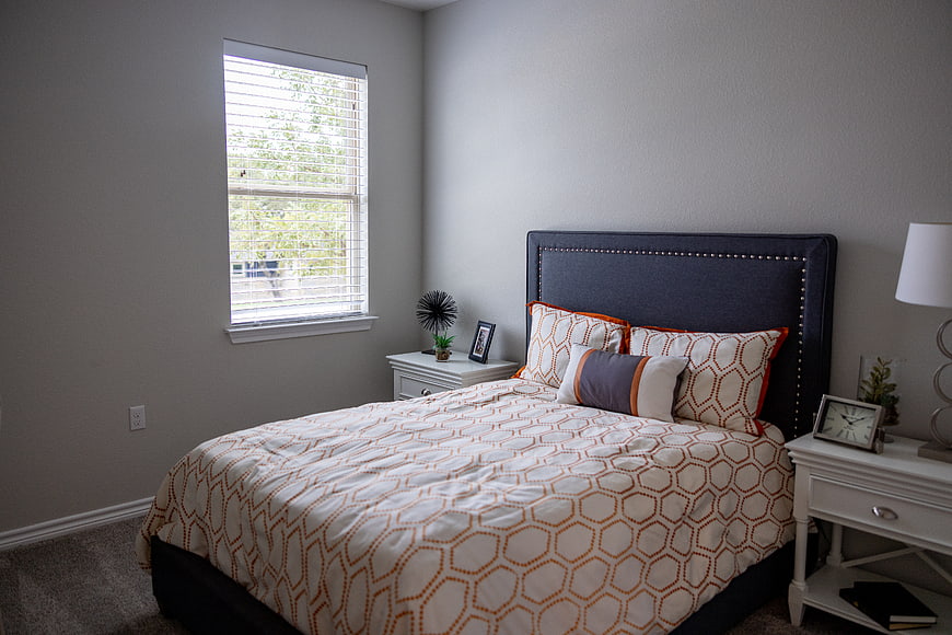 Modern Bedroom Interior with Navy Headboard and Orange Patterned Bedding