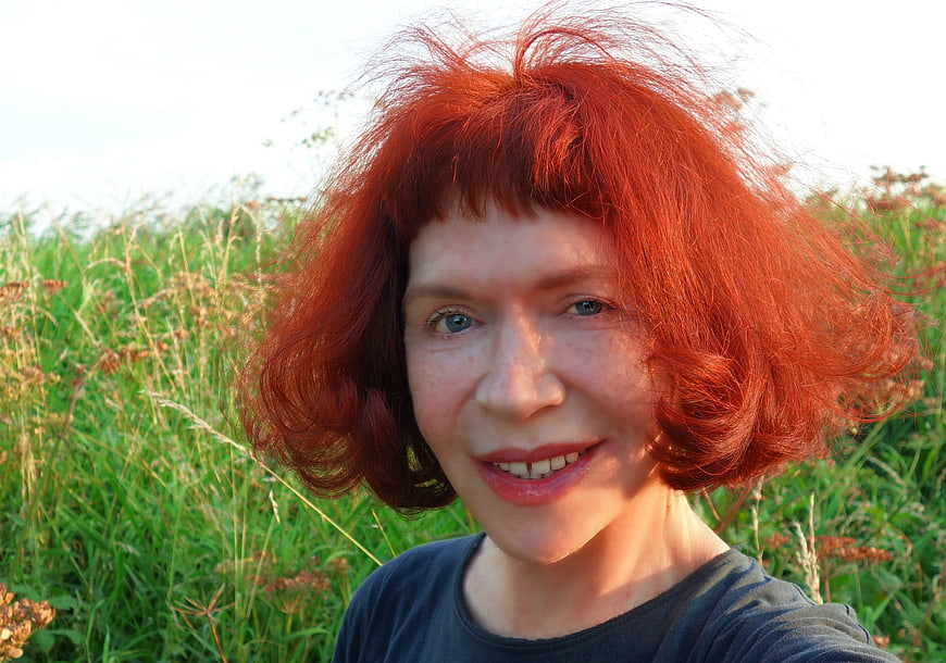 Portrait of smiling woman with red hair in field