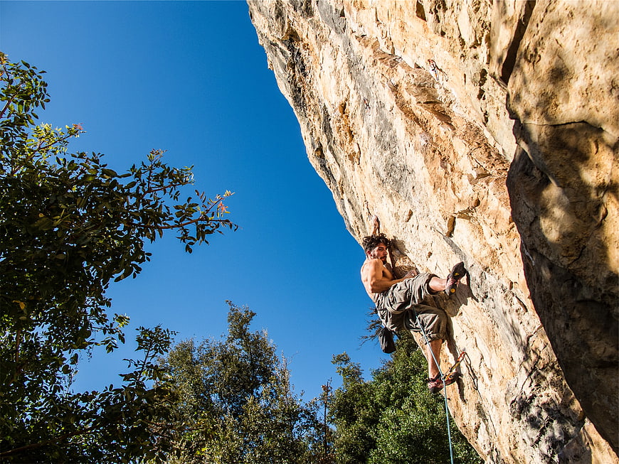 Muscular Man Rock Climbing on Sunny Day