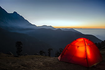 Glowing Orange Tent on Mountain Ridge at Sunset
