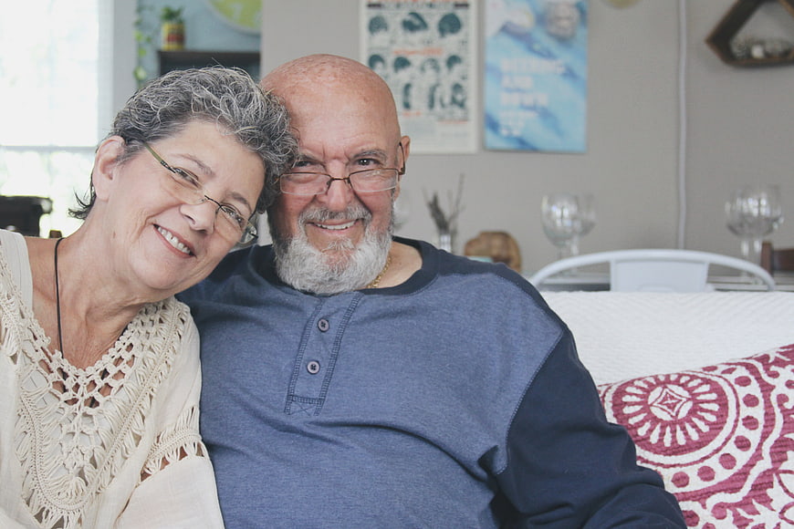 Happy Senior Couple Smiling Together on Sofa at Home