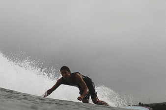Man Surfing on Wave with Overcast Sky