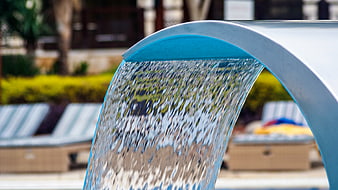 Close-up of water flowing from a curved pool fountain