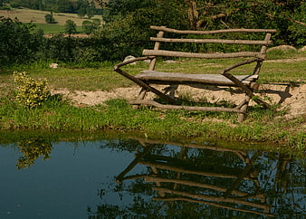 Rustic wooden bench by a pond with reflection