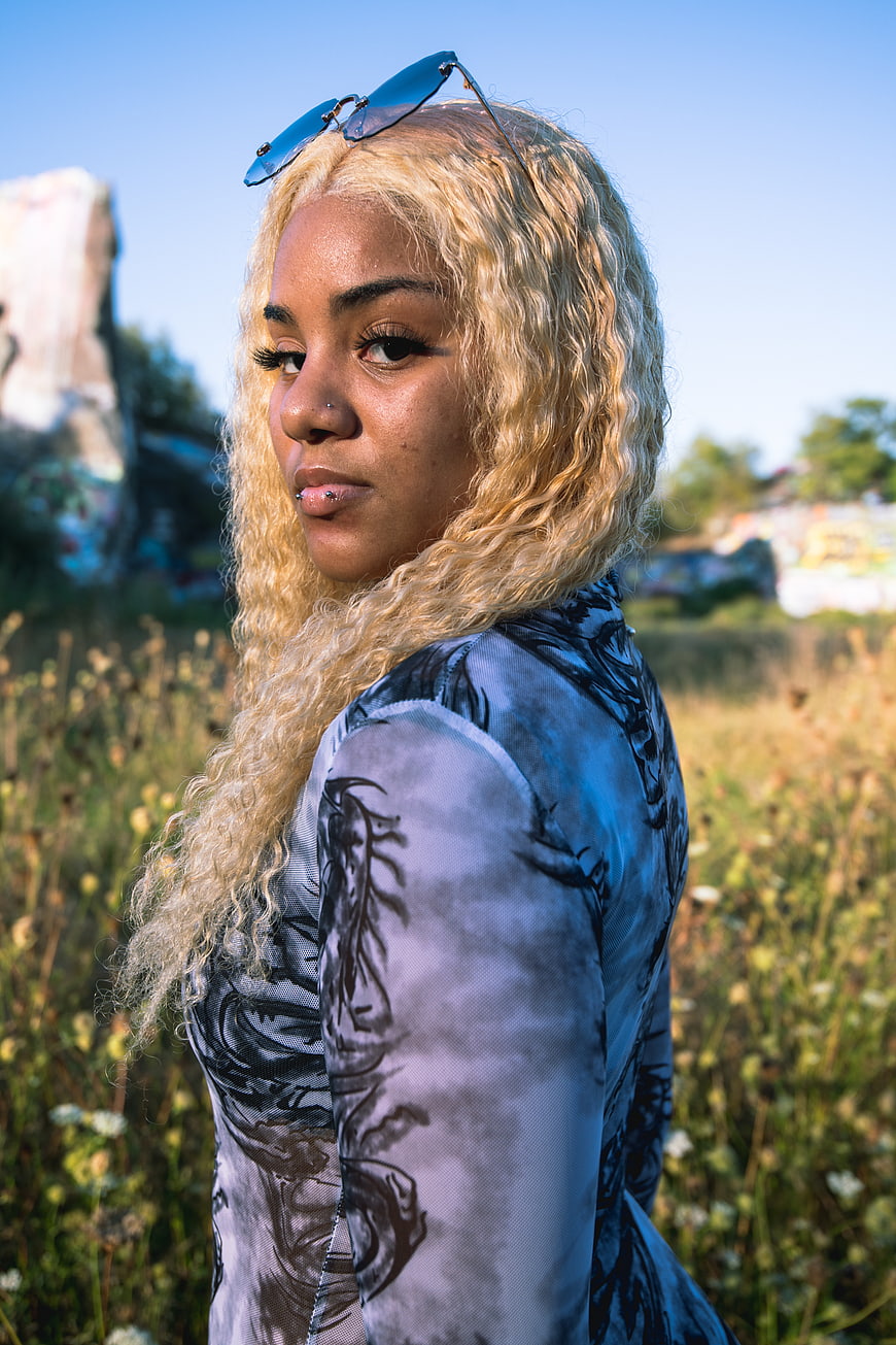 Stylish Woman with Blonde Curly Hair in Urban Field