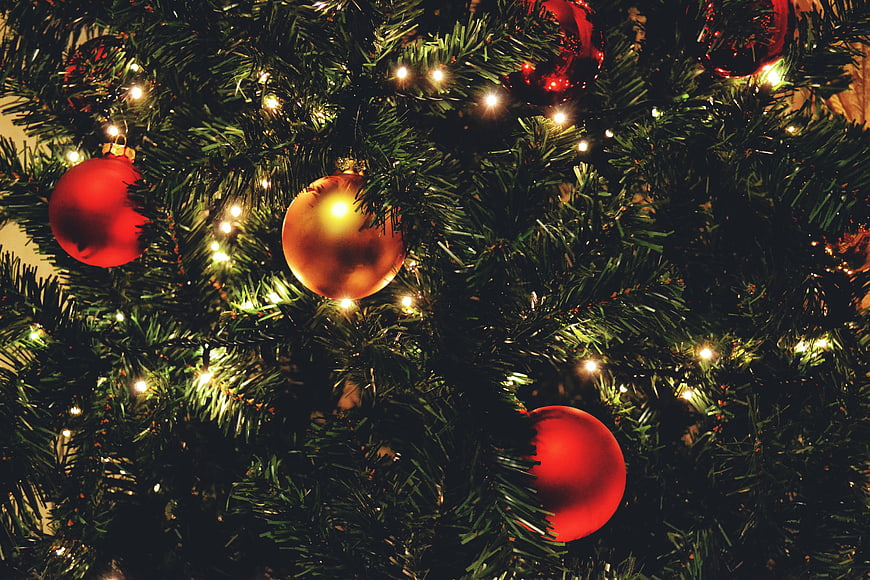 Close-up of Christmas tree with red and gold ornaments and warm lights