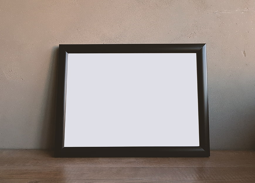 Empty black picture frame mockup on wooden shelf