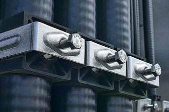 Close-up of galvanized steel cable clamps securing thick black cables