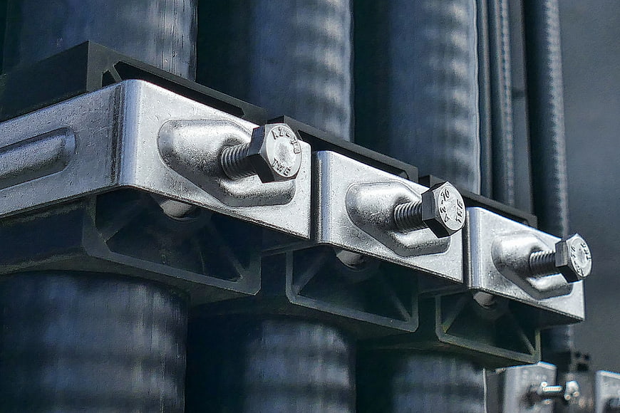 Close-up of galvanized steel cable clamps securing thick black cables