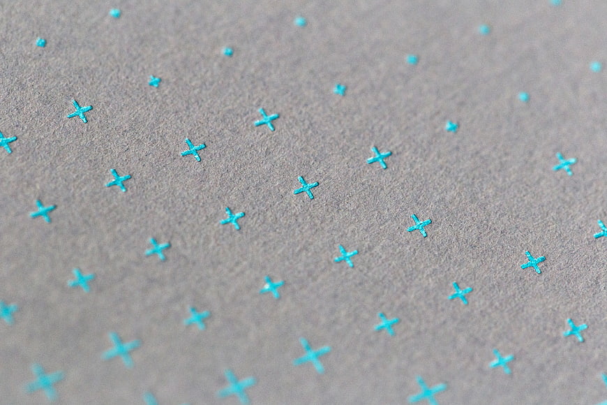 Close-up of textured gray paper with cyan cross pattern