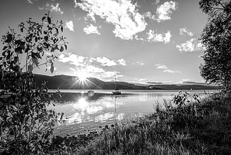 Black and white landscape of sailboats on calm water at sunset