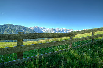 Wooden fence in alpine meadow with Dolomites mountains