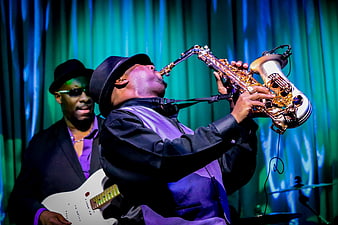 Jazz saxophonist performing live on stage with electric guitarist