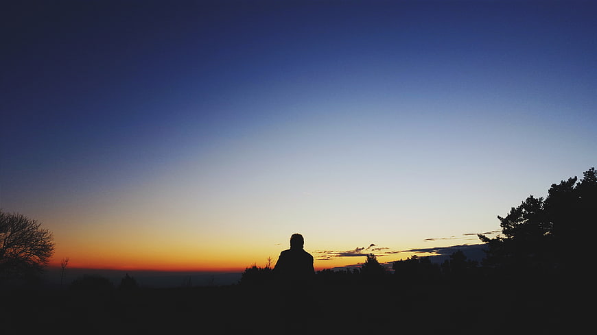 Silhouette of Man Watching Sunset Over Landscape