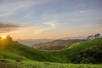Sunset Over Rolling Green Hills and Mountain Landscape