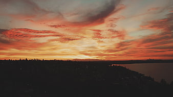 Dramatic Sunset Sky Over Silhouetted City and Water