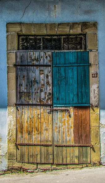 Weathered Wooden Door with Blue Shutters and Stone Frame