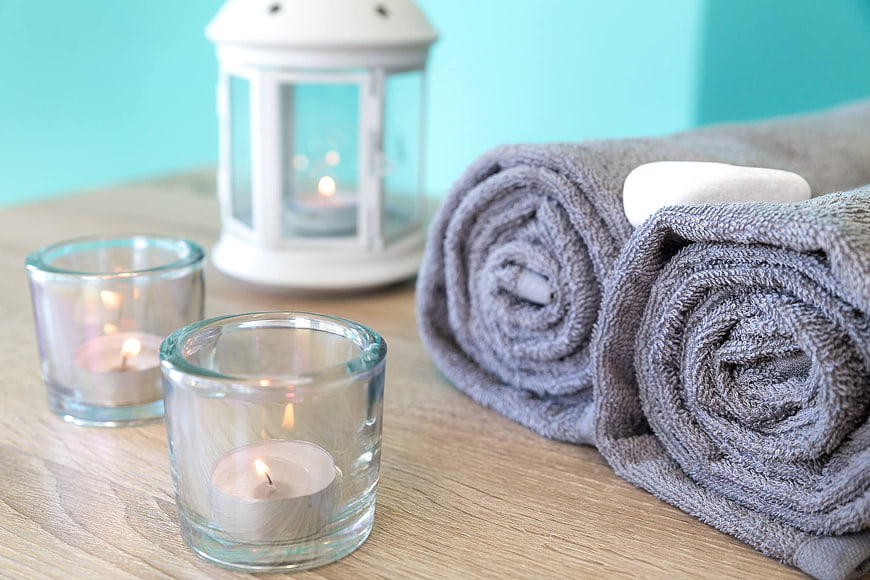 Spa relaxation setup with rolled towels and candles