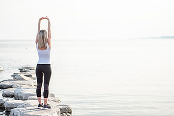 Woman Stretching on Rocks by the Ocean