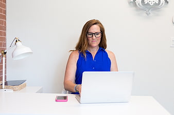 Professional woman working on laptop at white desk