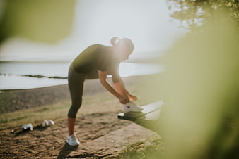 Woman Stretching Shoes on Outdoor Bench by Lake
