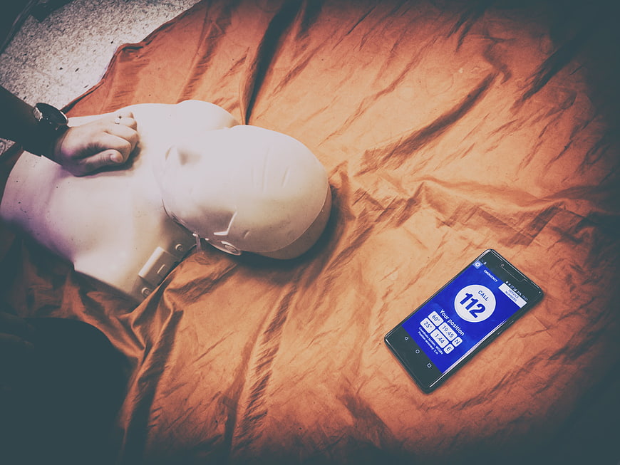 CPR Training Dummy With Smartphone Displaying 112 Emergency Call
