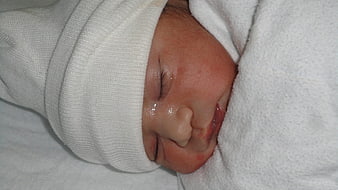 Newborn Baby Sleeping Peacefully Wrapped In White Hospital Blanket