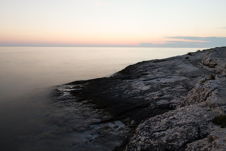 Serene rocky coastline at sunset with smooth ocean water