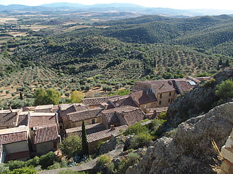 Aerial view of historic village with terracotta roofs overlooking olive groves