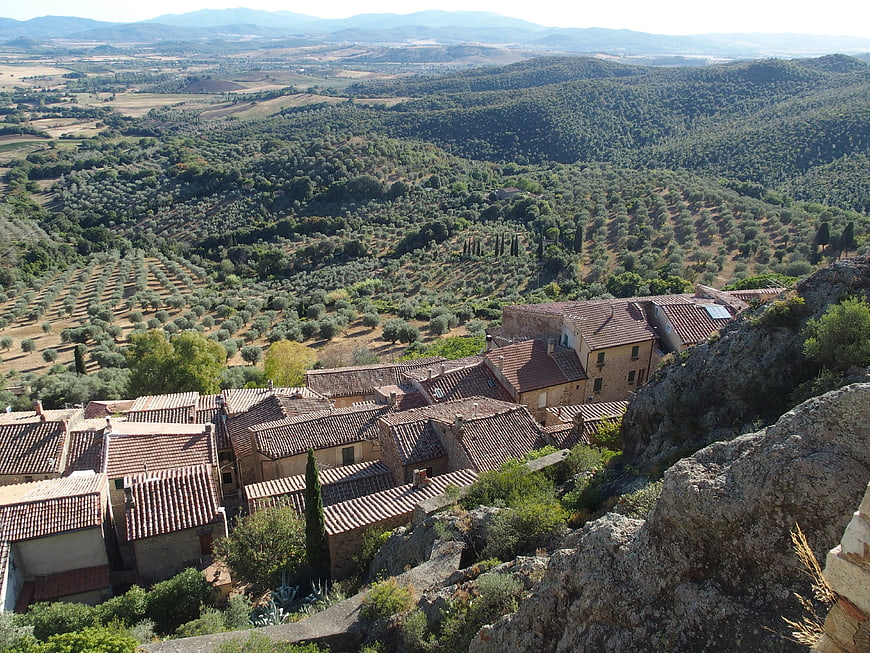 Aerial view of historic village with terracotta roofs overlooking olive groves