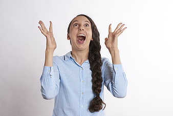 Excited woman with open mouth and raised hands on white background