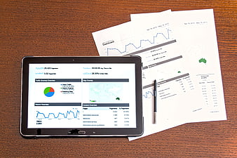 Tablet and printed reports showing website analytics dashboard on wooden desk