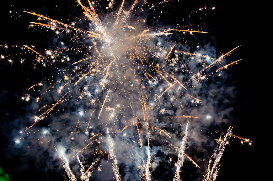 Golden fireworks exploding in night sky with smoke