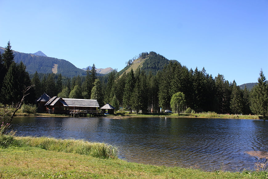 Serene Alpine Lake with Wooden Cabins and Mountain Backdrop