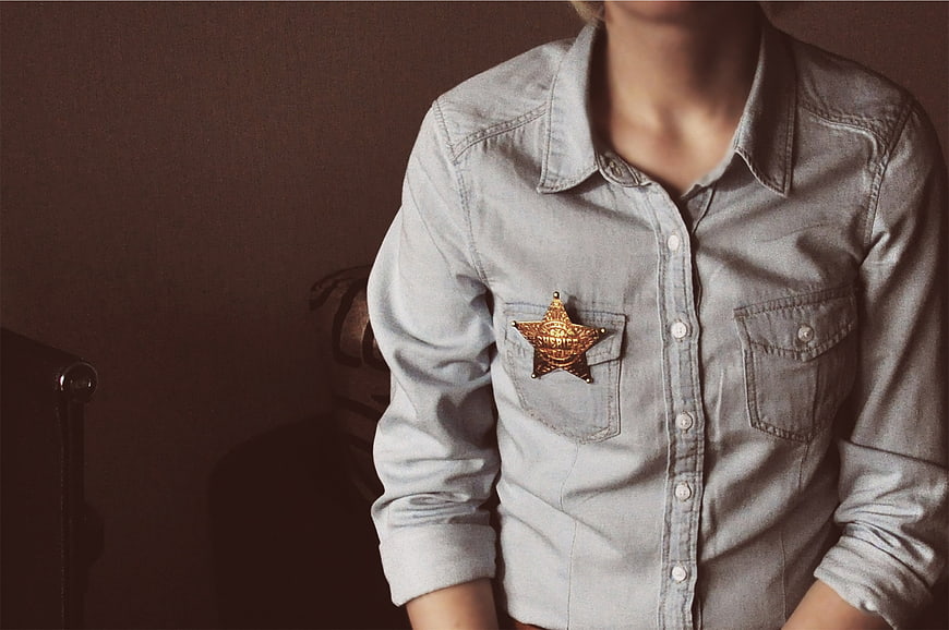 Person wearing denim shirt with sheriff badge