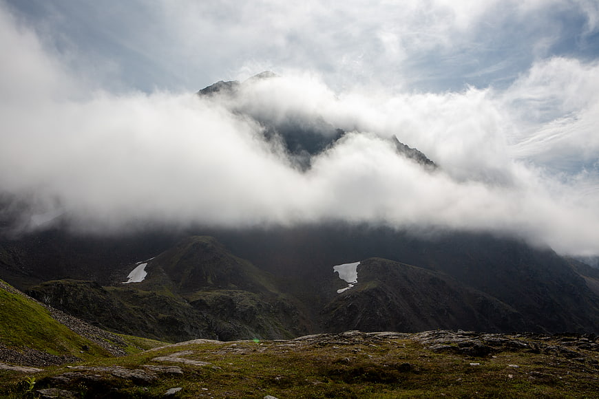 Misty Mountain Peak with Clouds and Green Slopes